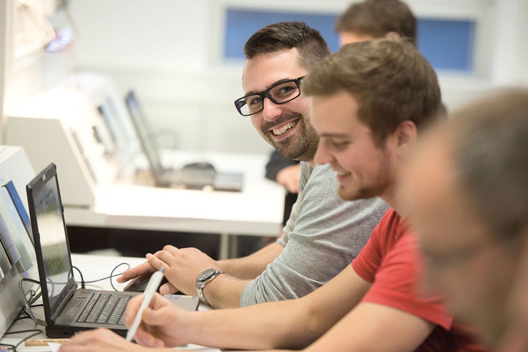 Employees working and smiling at a computer workstation in an office environment