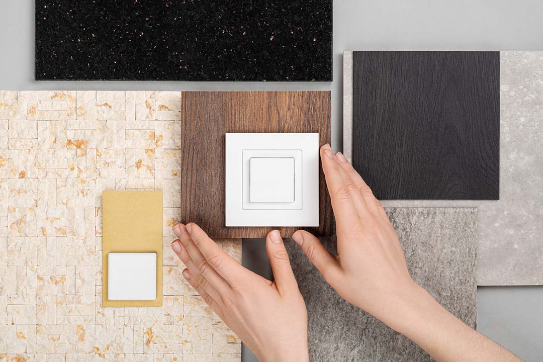 Personne assortissant un interrupteur mural blanc à différents échantillons de design d'intérieur