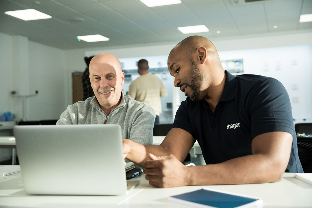 Two Hager employees discussing work on a laptop in a modern office setting