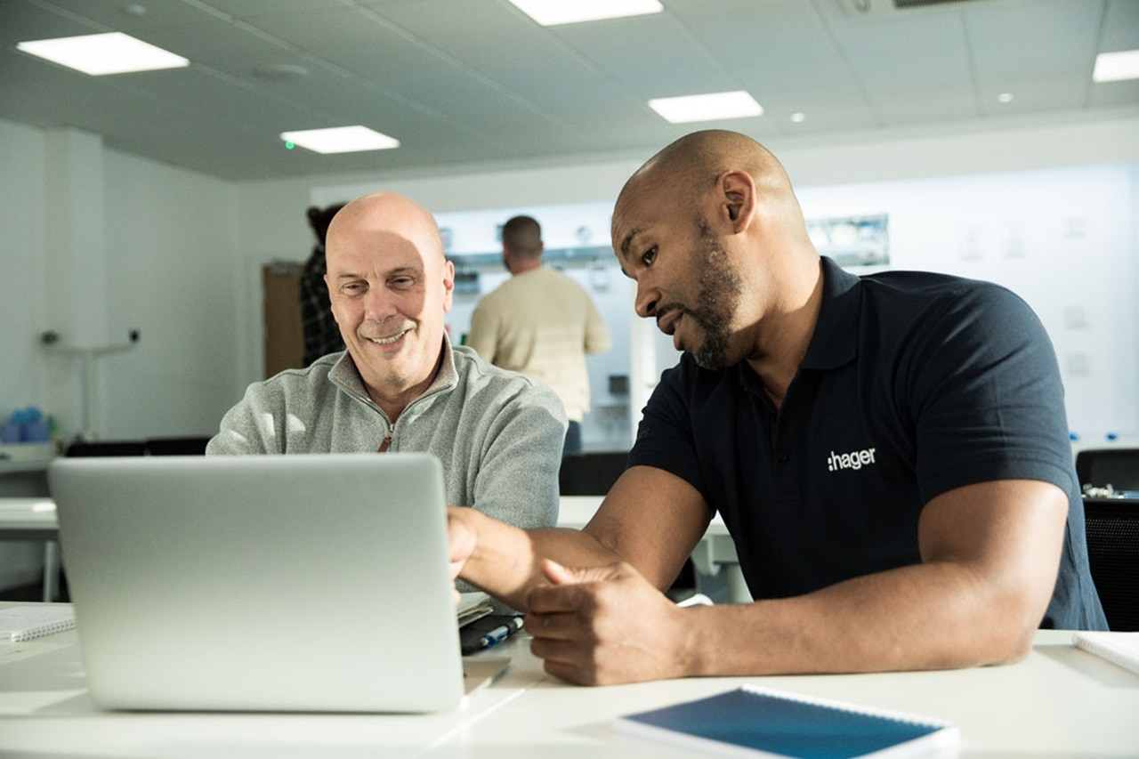 Two Hager employees discussing work on a laptop in a modern office setting